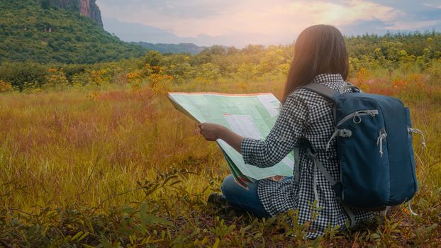 Hipster Asian woman backpacker look map on trip