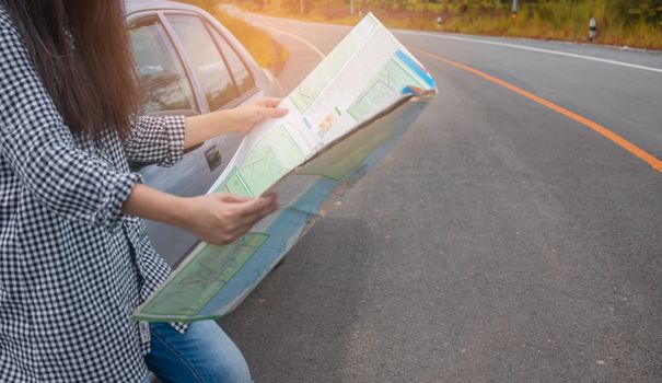 Hipster Asian woman backpacker look map on trip