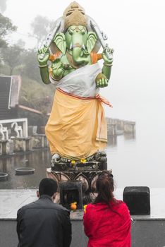 A kneeling man and woman pray in front of a Hindu deity, Grand Bassin Mauritius