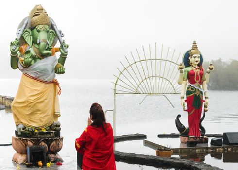 A kneeling woman pray in front of a Hindu deity, Grand Bassin Mauritius