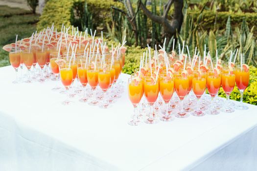 Orange juice cocktail in a flute glasses and slice of fresh orange with draw on white table,Party outdoor.