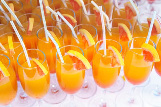 Orange juice cocktail in a flute glasses and slice of fresh orange with draw on white table,closed picture.