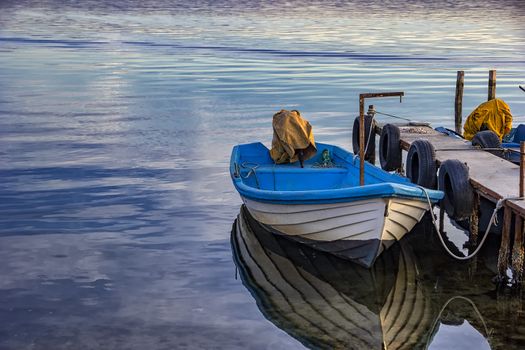 Boat with water reflection in the summer evening at a pier 