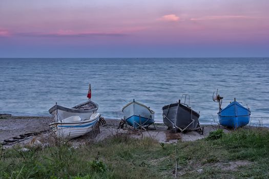 several wooden boats on the sand after sunset