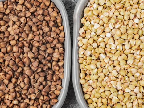 Top view of raw green buckwheat and brown roasted buckwheat on gray concrete background. Healthy food and diet concept. Flat lay. Copy space.