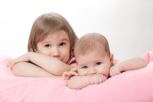 two little girls of the sisters lie on a pink plaid