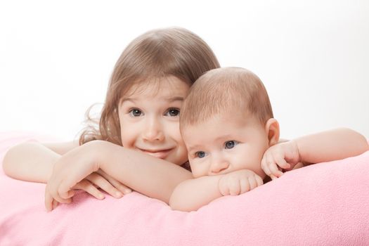 two little girls of the sisters lie on a pink plaid