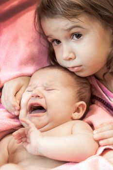 two little girls of the sisters lie on a pink plaid