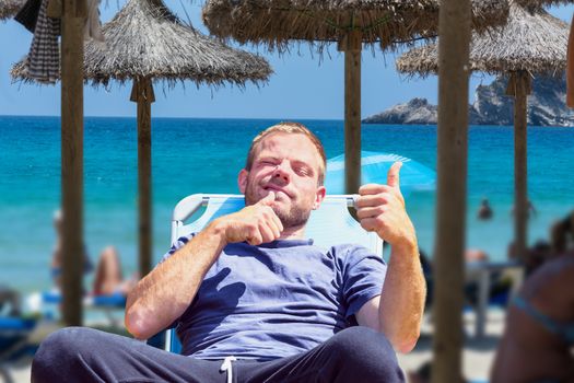 Beach life, beach holiday. Focus on man in deck chair. Background desired blur.