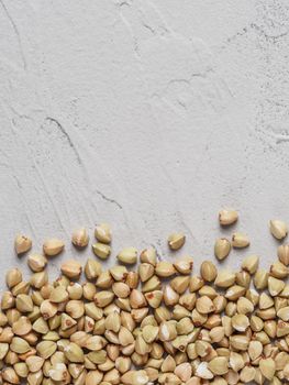 Raw green buckwheat on gray concrete background Healthy food and diet concept. Top view or flat lay. Vertical.