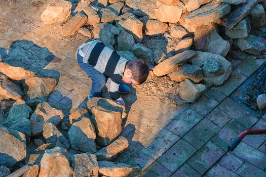 Little boy throwing a stone into a water barrel