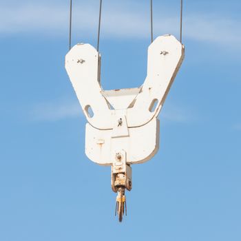 Old metal crane hook on blue sky background