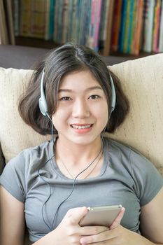 Close up young asian woman short hair listening music from mobile phone on the couch at home