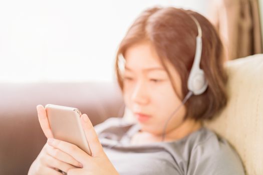 Close up young asian woman short hair listening music from mobile phone on the couch at home