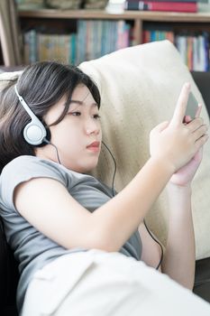 Close up young asian woman short hair listening music from mobile phone on the couch at home