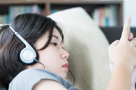 Close up young asian woman short hair listening music from mobile phone on the couch at home