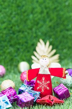 Celebration of New year and Christmas, Christmas angel doll and christmas decoration on green grass background