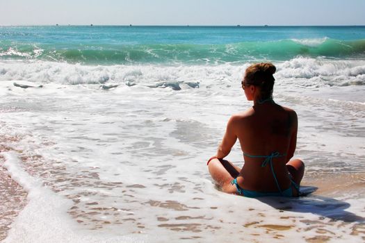 The girl is meditating on the ocean shore. Bali