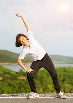 Fitness and lifestyle concept - Young asian woman short hair doing exercising outdoor and warm up preparing for jogging