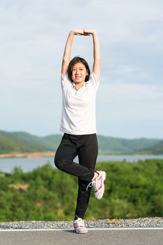 Fitness and lifestyle concept - Young asian woman short hair doing exercising outdoor and warm up preparing for jogging