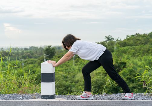 Woman runner doing exercises and warm up preparing for jogging outdoor