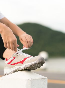 Woman runner tying shoelace his before starting running, Woman doing exercises and warm up before run daily routine workout