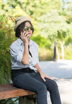 Beautiful and young women with short hair wearing hat use mobile phone in garden