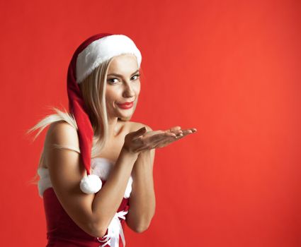 Beautiful santa claus girl blowing kiss on red christmas background