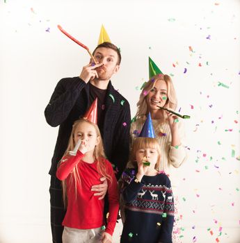 Family blowing party trumpets with confetti celebrating new year