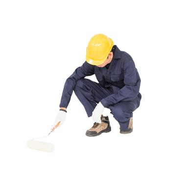 Young worker in a uniform using a paint roller is painting invisible floor, isolated on white background cutout