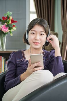 Close up beautiful young asian woman short hair listening music in living room at home