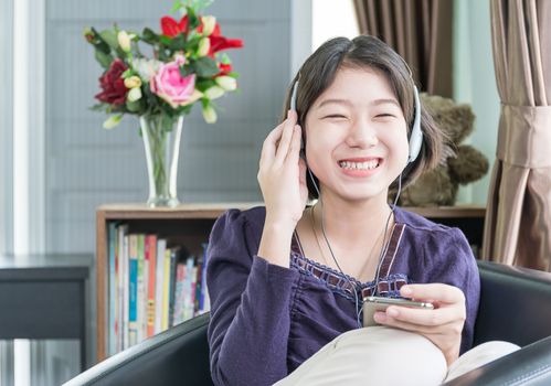 Close up beautiful young asian woman short hair listening music in living room at home