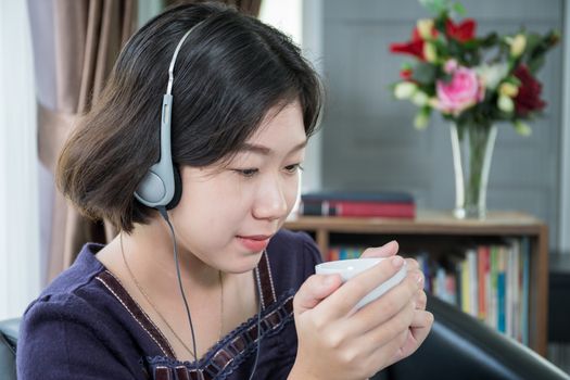 Close up beautiful young asian woman short hair listening music in living room at home