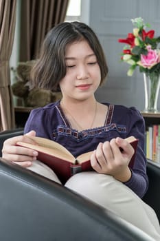 Close up beautiful young asian woman short hair read a book in living room at home