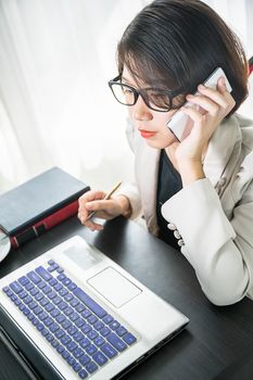 Young asian woman short hair in smart casual wear working on laptop while sitting near window in home office