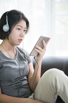 Close up young asian woman short hair listening music from mobile phone on the couch