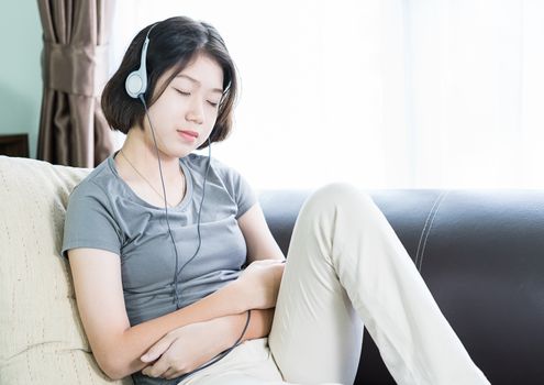 Close up young asian woman short hair listening music from mobile phone on the couch