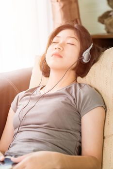 Close up young asian woman short hair listening music from mobile phone on the couch