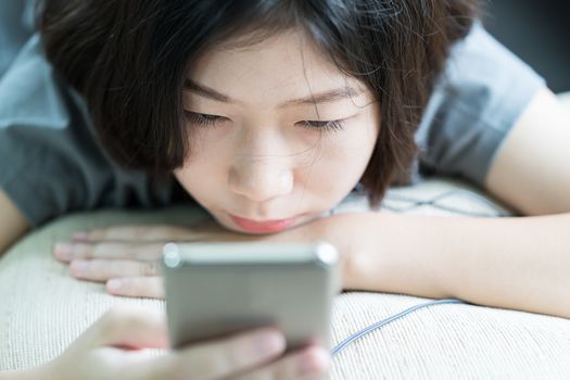 Close up young asian woman short hair listening music from mobile phone on the couch