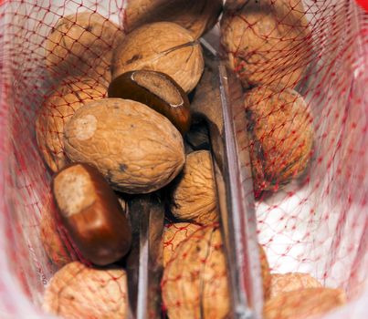 hazelnuts and walnuts in a red net container with a nutcracker