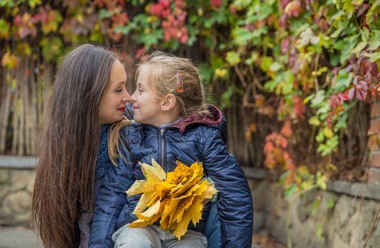 Mother and daughter nose-to-nose among autumn