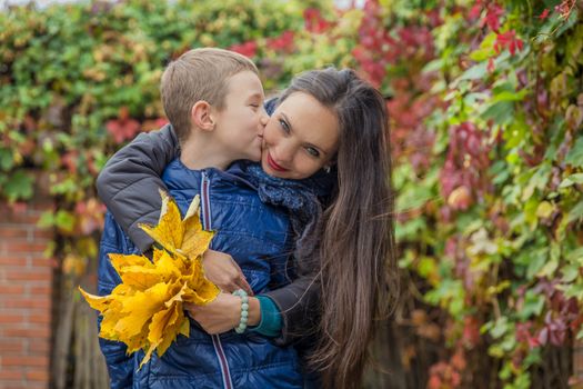 Son kissing mother among autumn outdoor