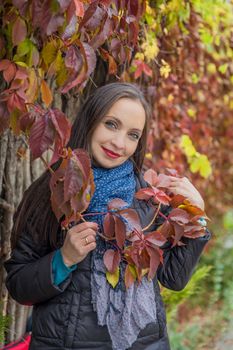 Pretty woman in red autumn foliage posing