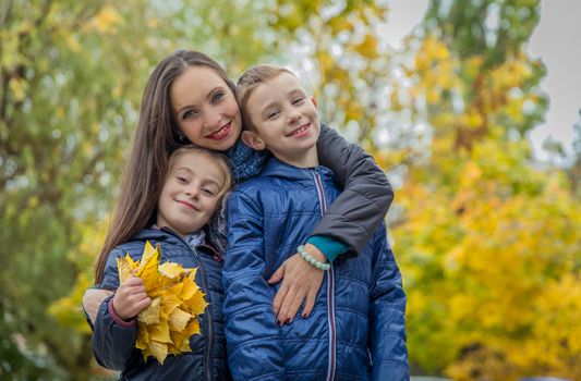 Happy mother and two children among autumn
