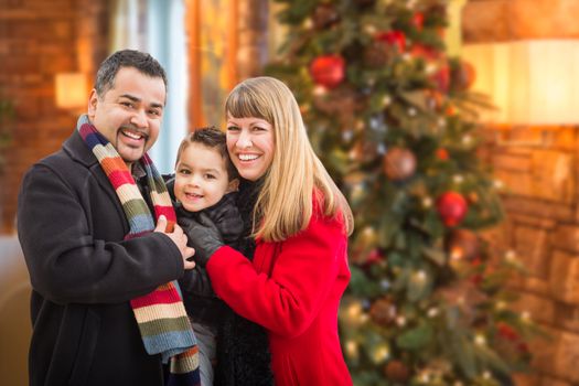 Young Mixed Race Family Portrait In Front of Christmas Tree Indoors.