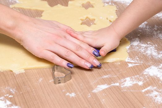 Christmas baking, mother and daughter cutting biscuits - cookies together from dough, hands only, no faces, xmas scene