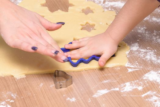 Christmas baking, mother and daughter cutting biscuits - cookies together from dough, hands only, no faces, xmas scene