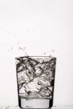 Crystals of ice falling into the glass of water