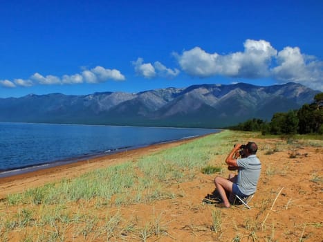 Two men with binoculars looking at the seashore