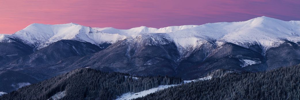 Nice panorama. Magic hour in the mountains at winter. Pink sky. Snowy ridge.